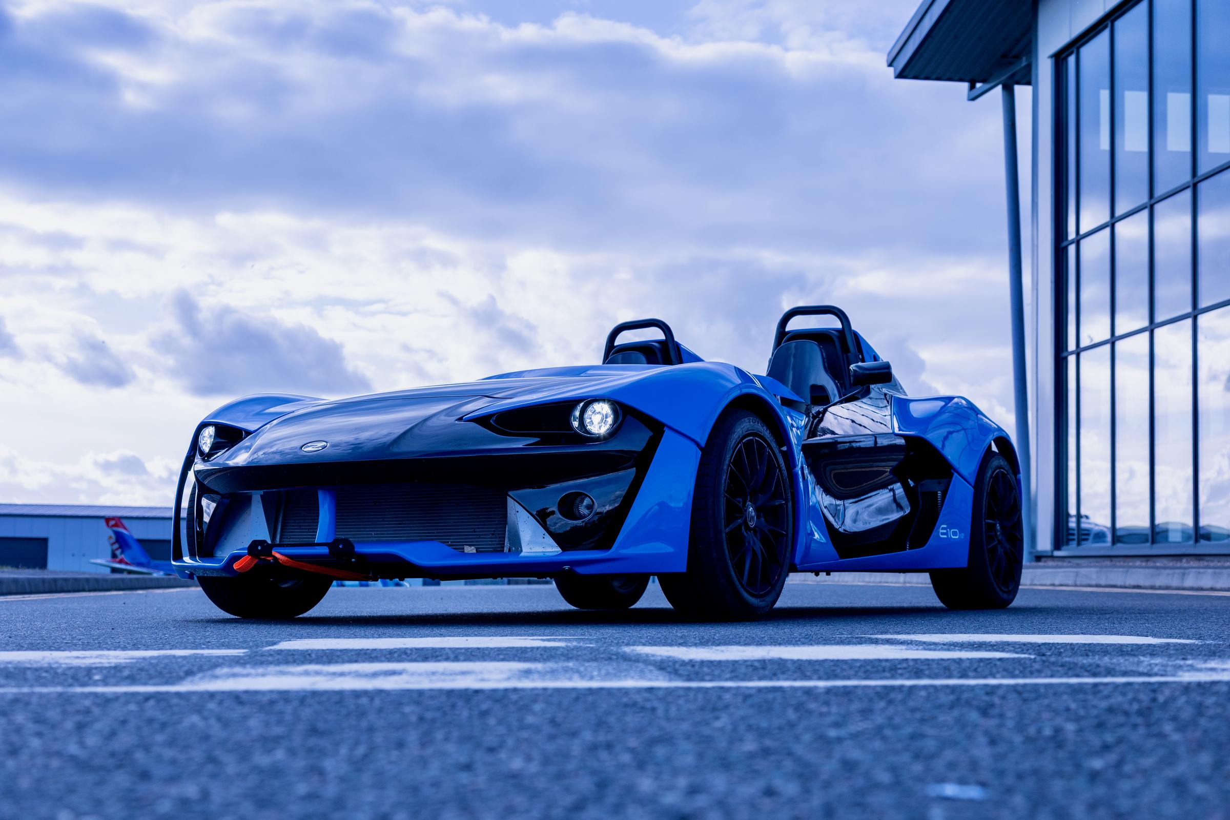 Zenos E10 front three quarter view beside a glass building